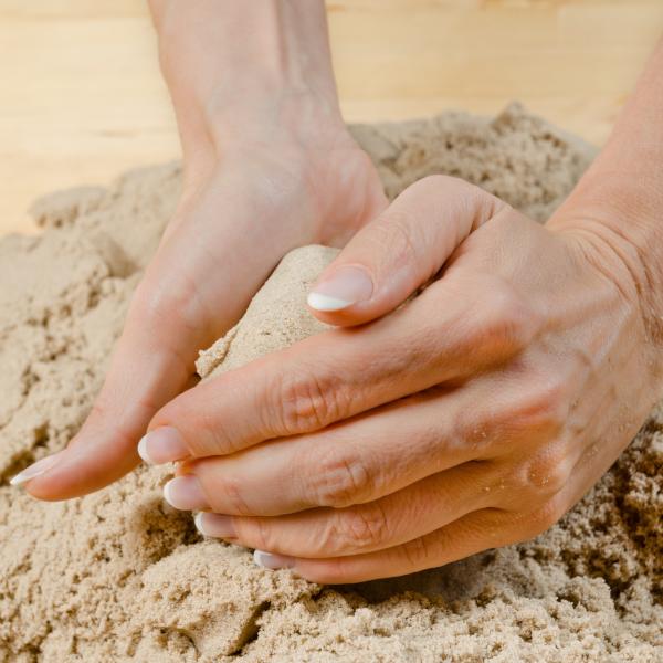 Zwei Hände die im Sand etwas formen?